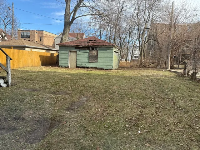 a view of a house with a yard and table and chairs under an umbrella