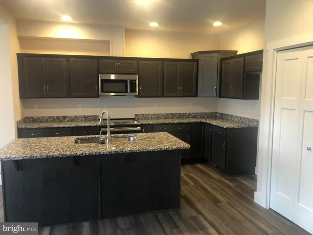 a kitchen with stainless steel appliances granite countertop a sink a stove and a wooden cabinets