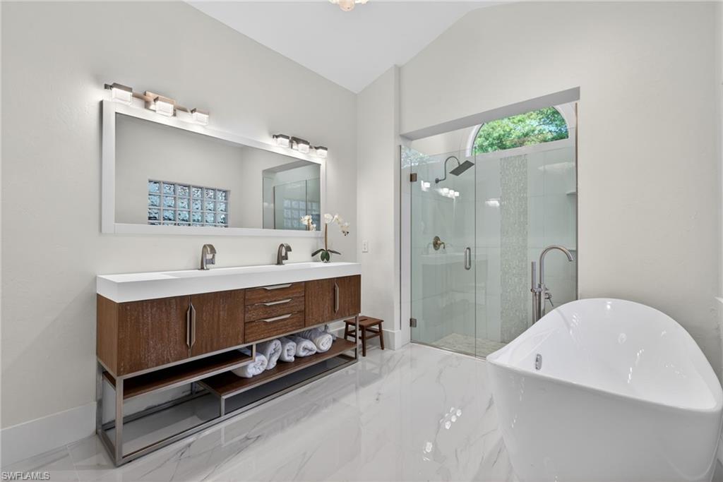 7657 Ponte Verde Way Naples, FL 34109 - Photo 22 of 41 a bathroom with a double vanity sink a mirror and a bathtub