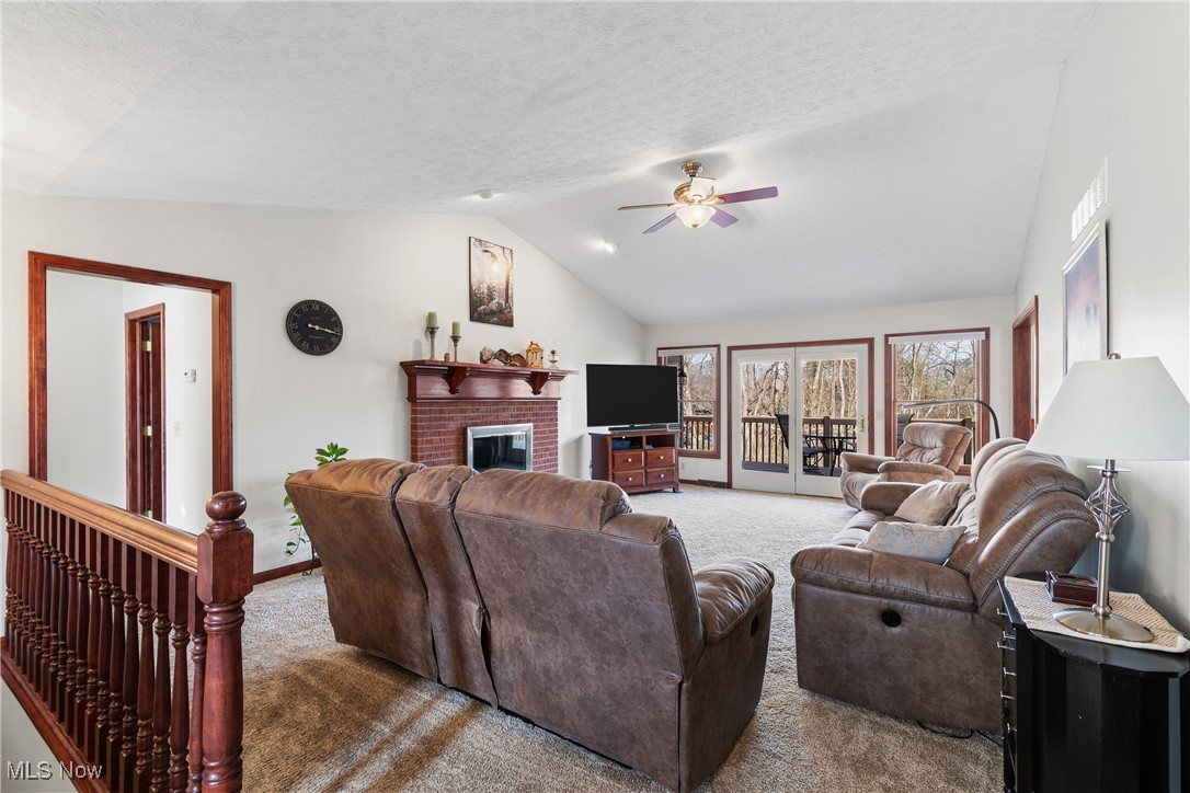 3393 Friendsville Road Wooster, OH 44691 - Photo 3 of 34 Carpeted living room featuring baseboards, a ceiling fan, vaulted ceiling, a textured ceiling, and a fireplace