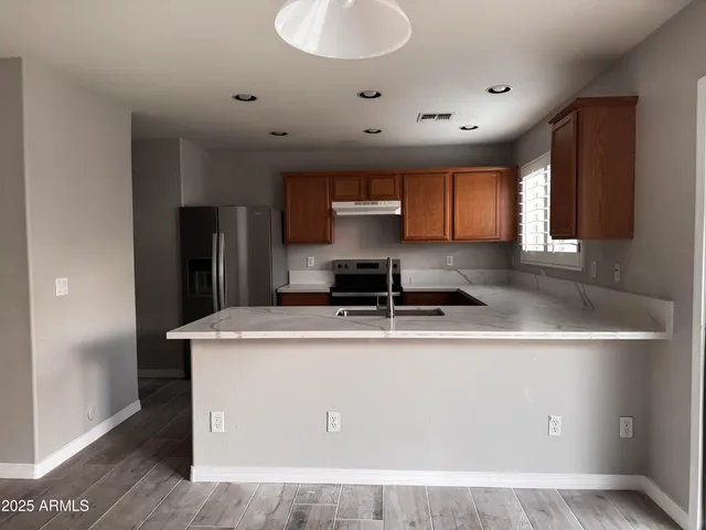 a kitchen with kitchen island granite countertop a sink a stove and a refrigerator