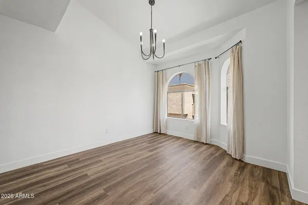 a view of an empty room with wooden floor kitchen and a window