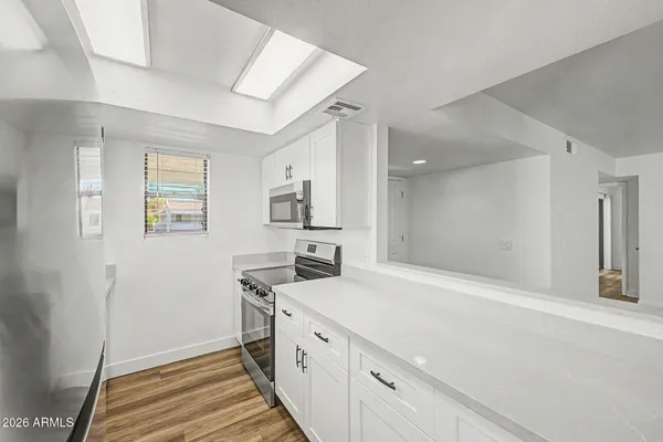 a large white kitchen with a sink and wooden floor