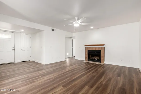 an empty room with wooden floor fireplace and windows