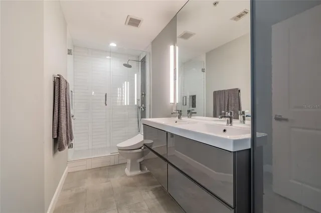 a bathroom with a double vanity sink toilet and shower