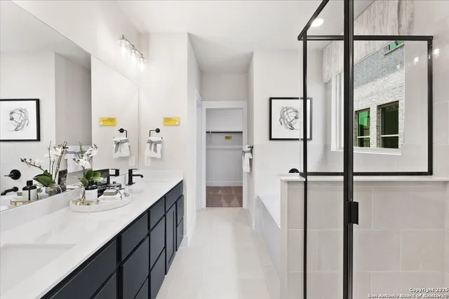 a en suite bathroom with a double vanity sink a mirror and a bathtub