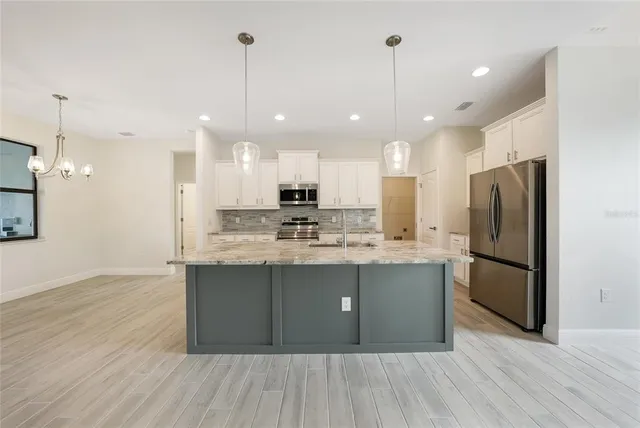 a kitchen with stainless steel appliances granite countertop a refrigerator a oven a sink dishwasher and a refrigerator with wooden floor