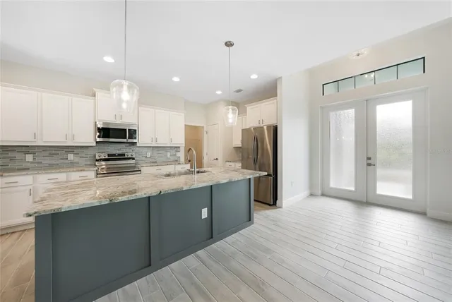 a kitchen with stainless steel appliances granite countertop a sink a microwave a stove and white cabinets