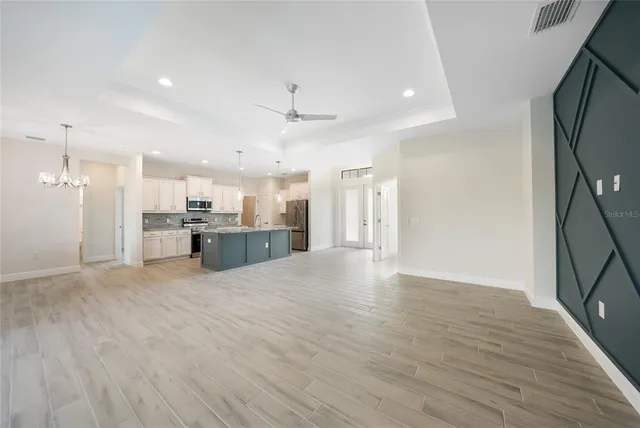 a large kitchen with stainless steel appliances kitchen island a large counter top a stove and a wooden floors