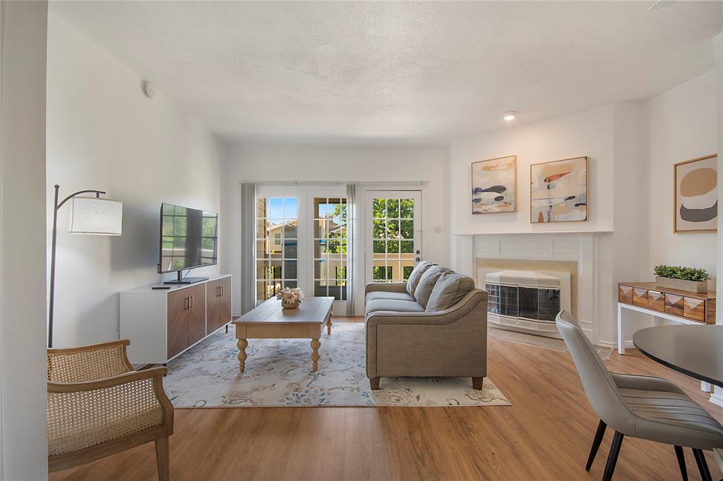 14277 Preston Road, Unit 823 Dallas, TX 75254 - Photo 18 of 31 Living area featuring a white mantel fireplace, wood-finish flooring, recessed lighting, and a double French door balcony entry