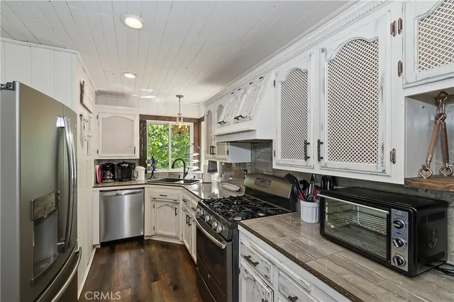 a kitchen with granite countertop a sink stainless steel appliances and cabinets