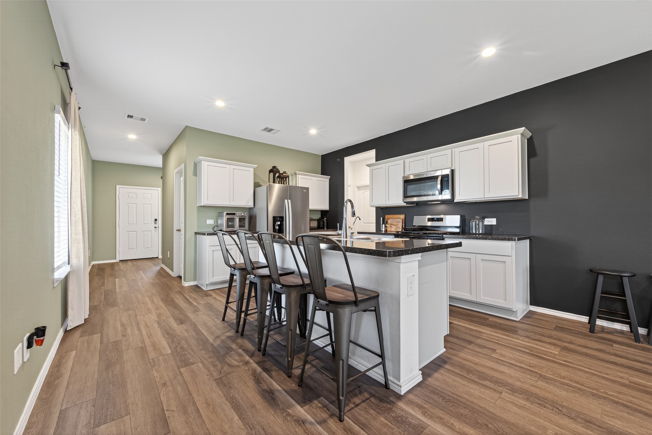 24251 Copperleaf Bay Ln Spring Spring, TX 77373 - Photo 7 of 42 a kitchen with stainless steel appliances granite countertop a refrigerator a stove top oven a dining table and chairs with wooden floor