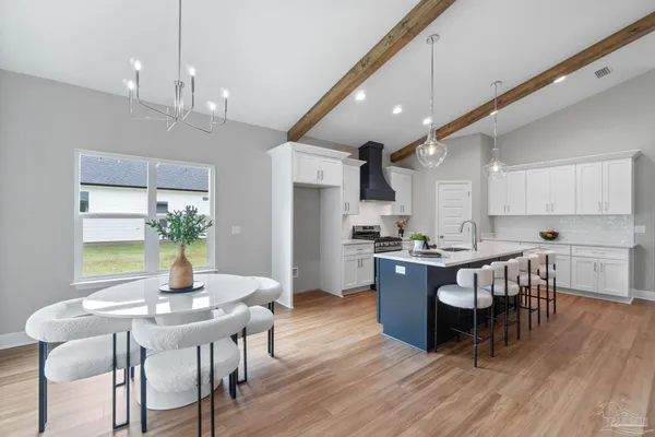 a kitchen with kitchen island granite countertop a dining table chairs stainless steel appliances and cabinets