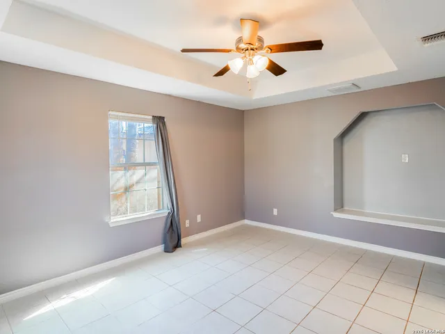 an empty room with windows and fan