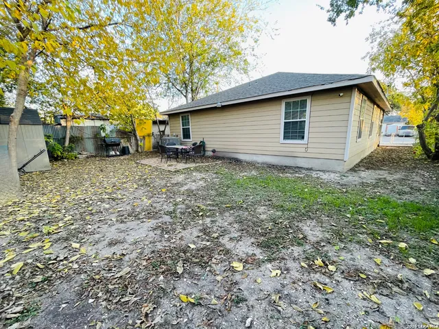 a backyard of a house with large trees and brick walls