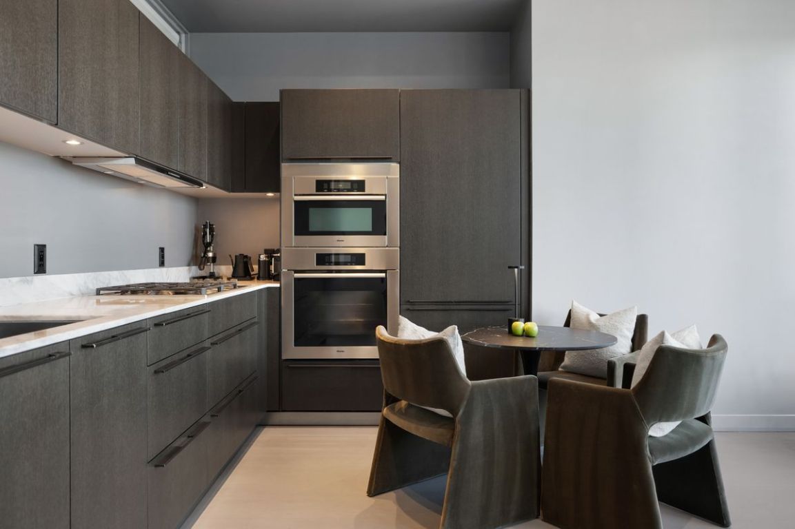 210 Lavaca Street, Unit 2809 Austin, TX 78701 - Photo 9 of 30 Kitchen featuring stainless steel appliances, modern cabinets, exhaust hood, dark brown cabinets, and light stone counters