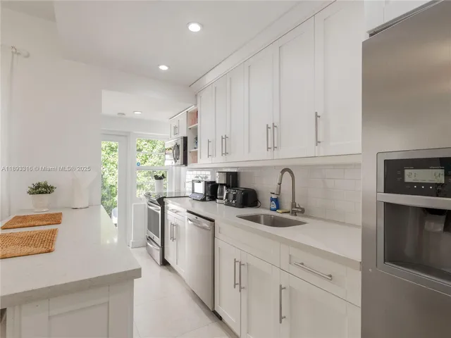 a kitchen with white cabinets sink and stainless steel appliances