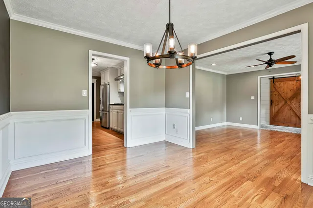 a view of a hallway with wooden floor and chandelier