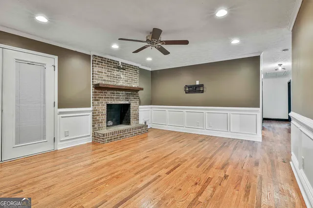 a view of an empty room with wooden floor fireplace and a window