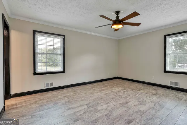 an empty room with ceiling fan and windows