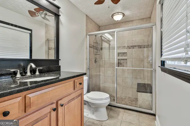 a bathroom with a granite countertop sink a toilet and shower