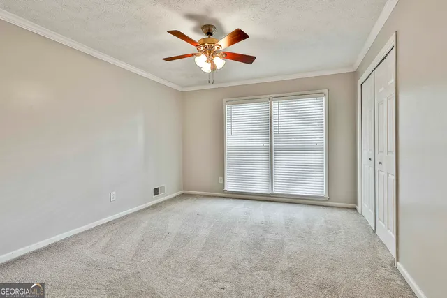 an empty room with chandelier fan and windows