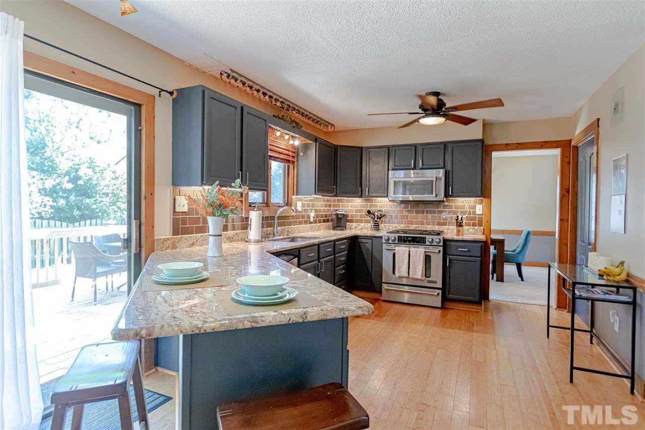 2521 Scouting Trail Raleigh, NC 27615 - Photo 11 of 29 a kitchen with stainless steel appliances granite countertop a stove a refrigerator a sink a dining table and chairs with wooden floor