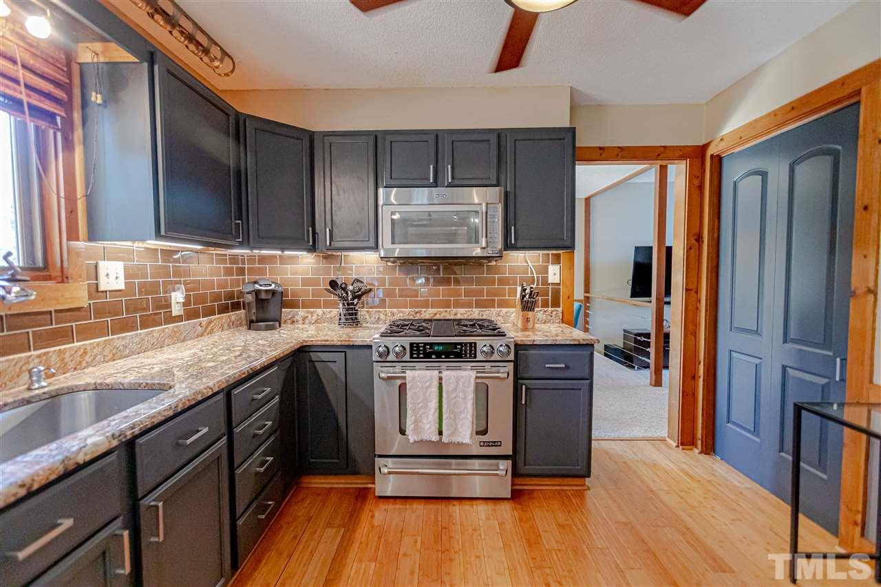 2521 Scouting Trail Raleigh, NC 27615 - Photo 12 of 29 a kitchen with kitchen island granite countertop wooden floors and stainless steel appliances