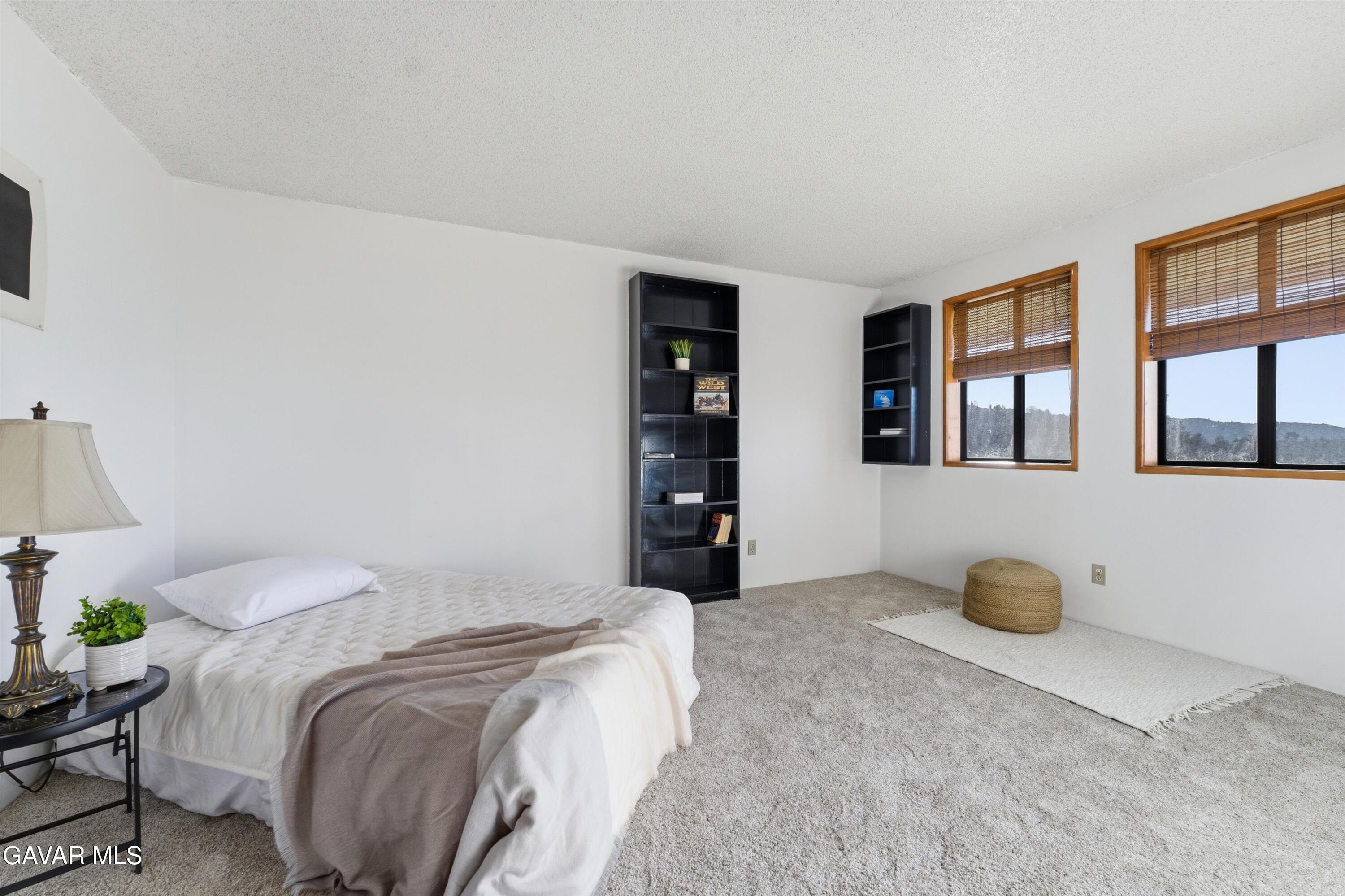 26181 Bear Valley Road Tehachapi, CA 93561 - Photo 15 of 38 a bedroom with a bed and a cabinets