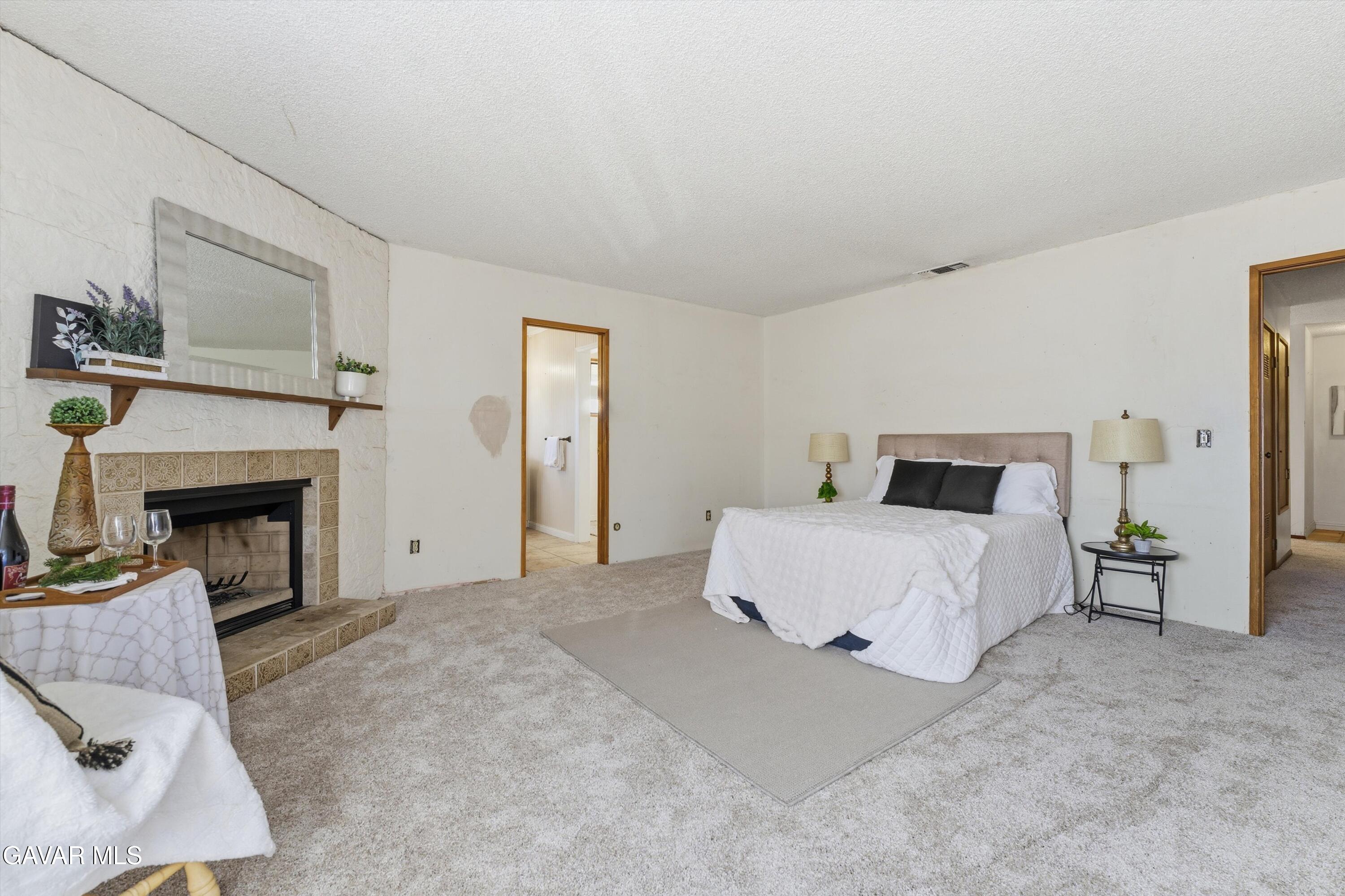 26181 Bear Valley Road Tehachapi, CA 93561 - Photo 27 of 38 a spacious bedroom with a bed and a fireplace