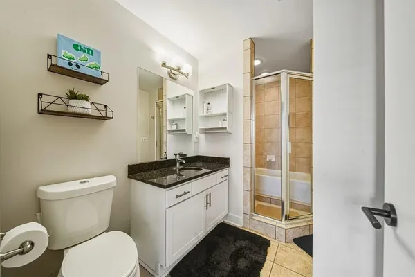 a bathroom with a granite countertop toilet a sink and a shower