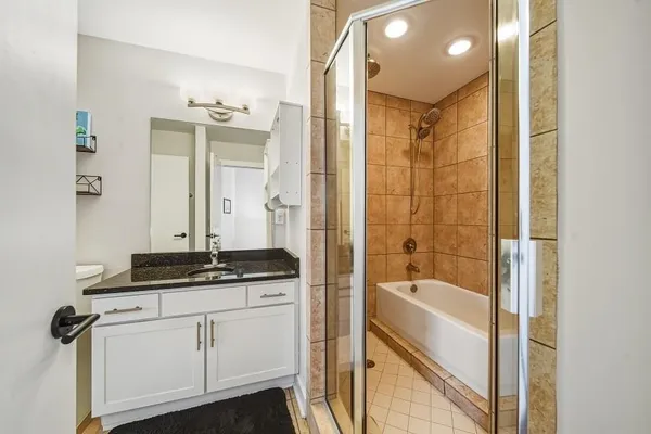 a bathroom with a granite countertop sink a mirror and a bathtub