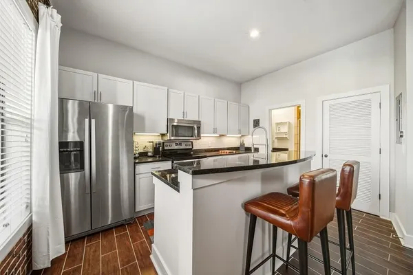a kitchen with stainless steel appliances a refrigerator a stove a sink dishwasher and a refrigerator with wooden floor