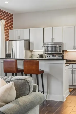 a living room with stainless steel appliances furniture and a kitchen view