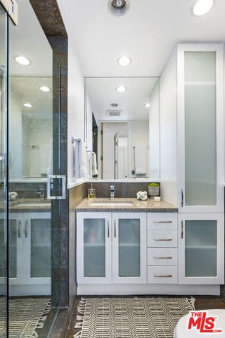 a bathroom with a granite countertop sink a mirror and a shower