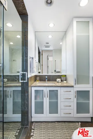 a bathroom with a granite countertop sink a mirror and a shower