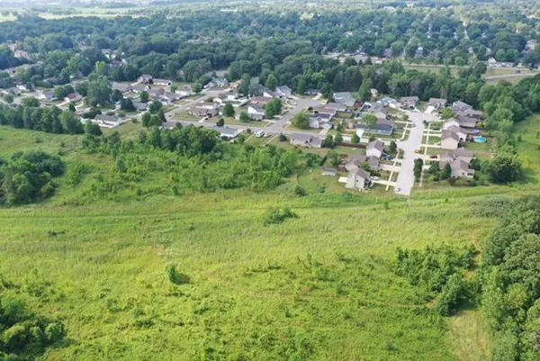 a view of a green field with lots of trees in the background