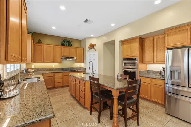 a kitchen with stainless steel appliances granite countertop a table chairs sink refrigerator and cabinets