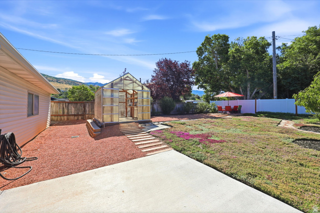 1180 North 400 East Bountiful, UT 84010 - Photo 35 of 50 Spacious backyard featuring a greenhouse, concrete patio, and a privacy fence