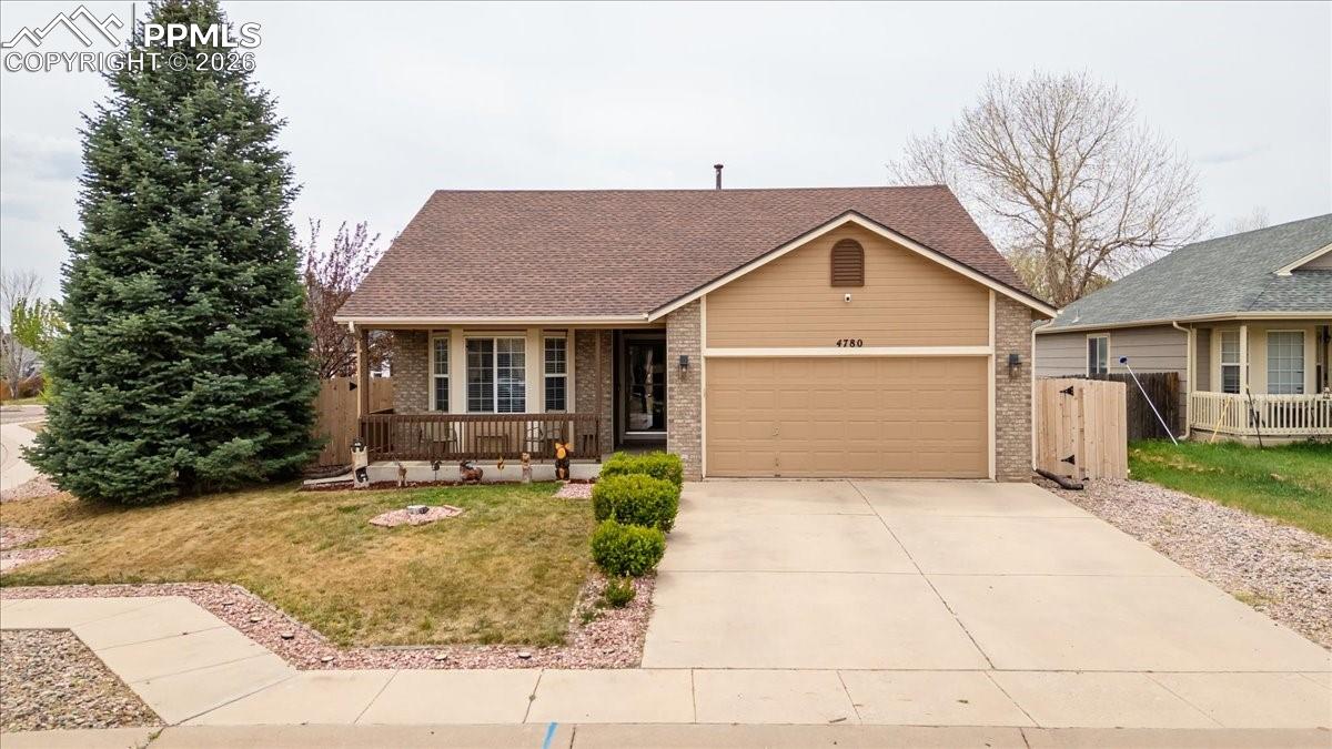 4780 Brant Road Colorado Springs, CO 80911 - Photo 1 of 49 View of front of property with brick siding, a garage, concrete driveway, covered porch, and a front lawn