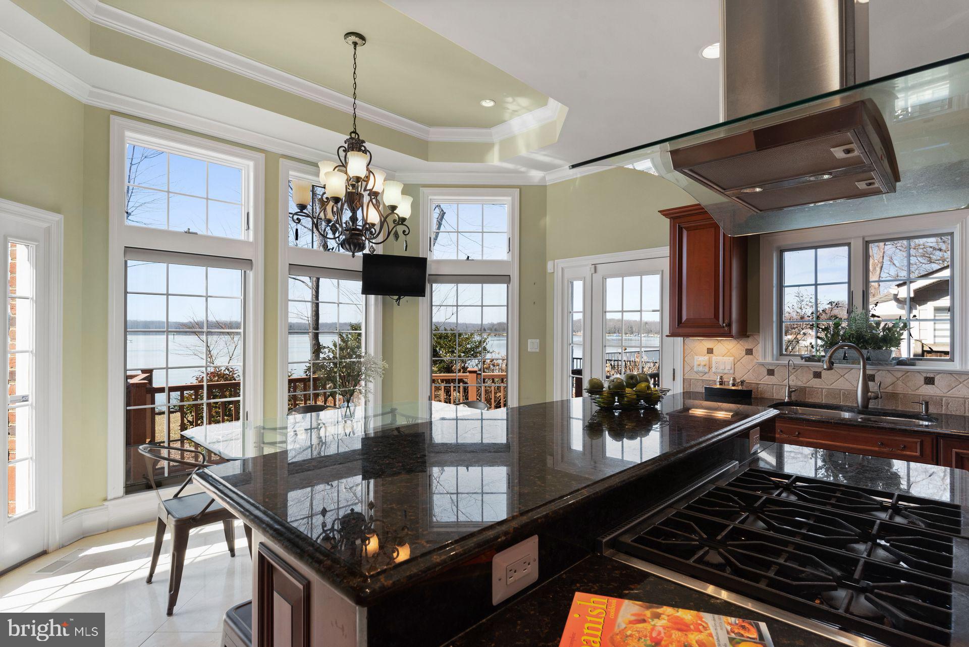 4132 Cadle Creek Road Edgewater, MD 21037 - Photo 27 of 85 a kitchen area with stainless steel appliances granite countertop a stove top oven a dining table and chairs with wooden floor