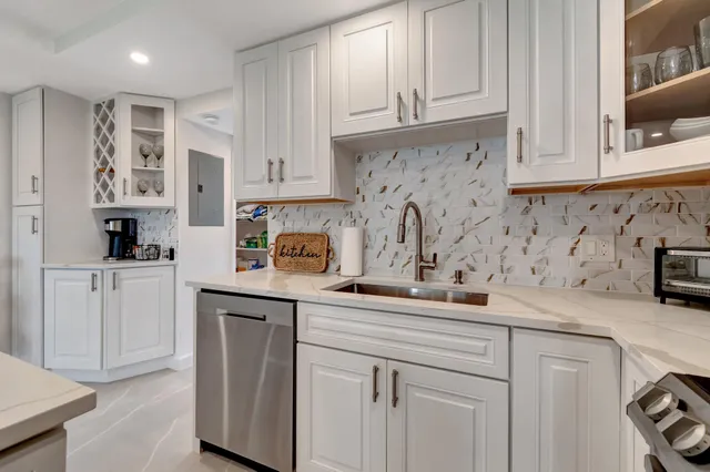 a kitchen with white cabinets and sink