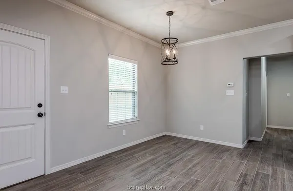 a view of empty room with wooden floor and window