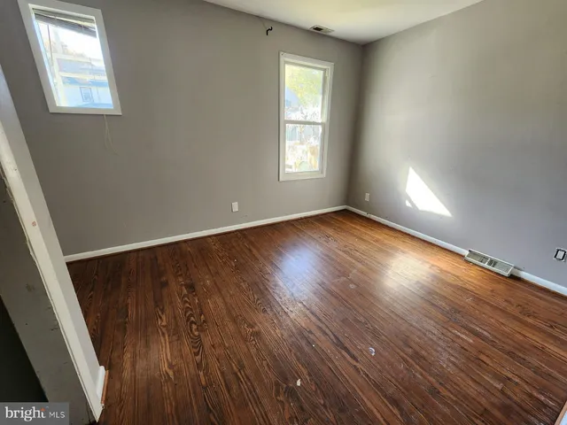 a view of an empty room with wooden floor and window