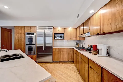a kitchen with stainless steel appliances a sink dishwasher stove refrigerator and cabinets
