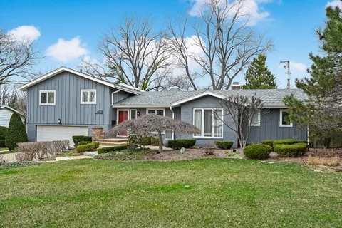 a front view of a house with a garden and trees