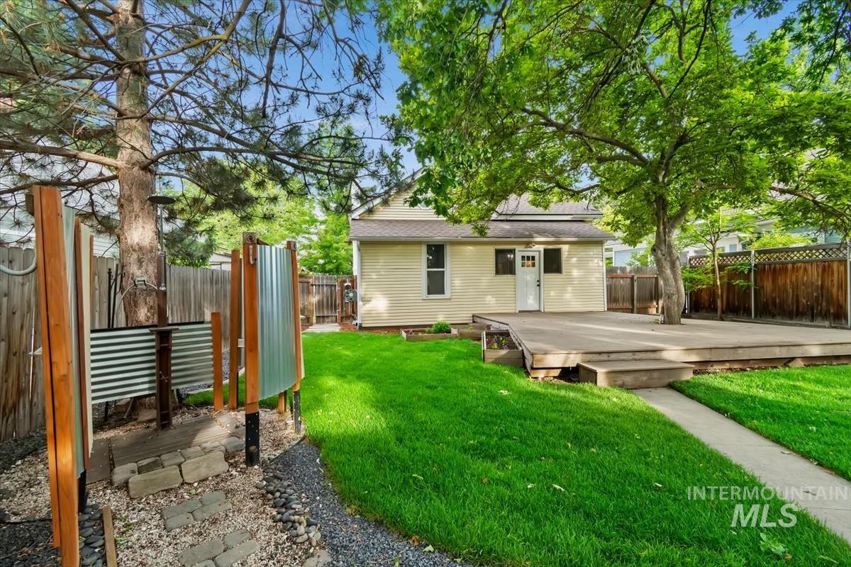 910 North 16th Street Boise, ID 83702 - Photo 35 of 47 Spacious backyard featuring a large elevated wood deck, verdant lawn, mature shade trees, and a privacy fence