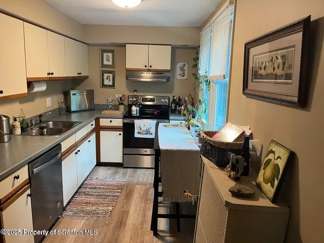 a kitchen with stainless steel appliances granite countertop a stove top oven a sink dishwasher and cabinets with wooden floor