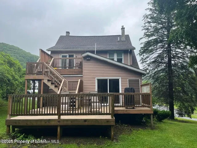 a view of a house with a deck and a yard