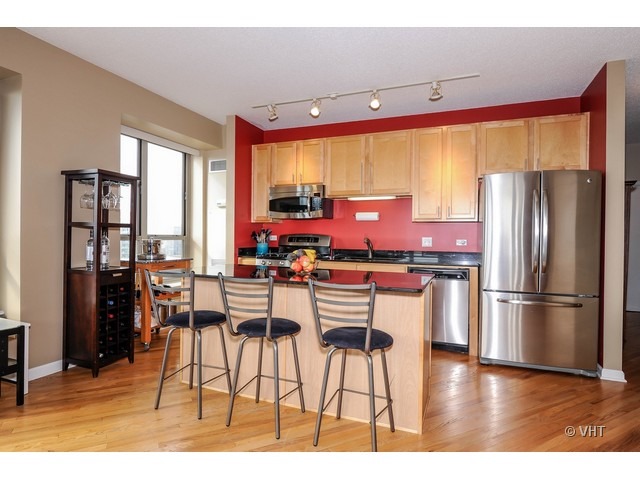 1717 South Prairie Avenue, Unit 1806 Chicago, IL 60616 - Photo 3 of 13 a kitchen with stainless steel appliances kitchen island granite countertop a refrigerator a stove a kitchen island with chairs and wooden floor